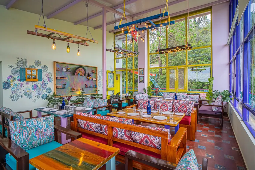 Sunlit dining area with tables, chairs, large windows, and decor items indoors