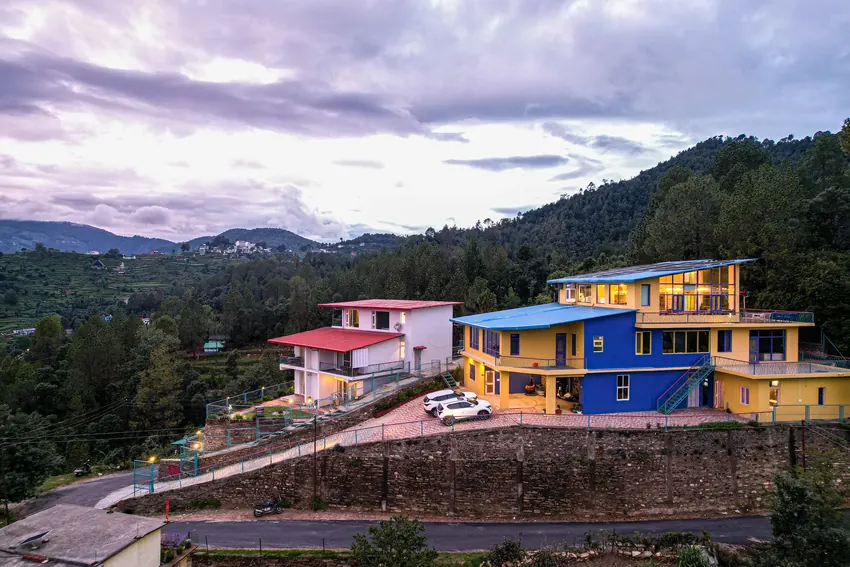 Aerial vista of luxury resort cottages, stone pathways, and mountains under cloudy sky
