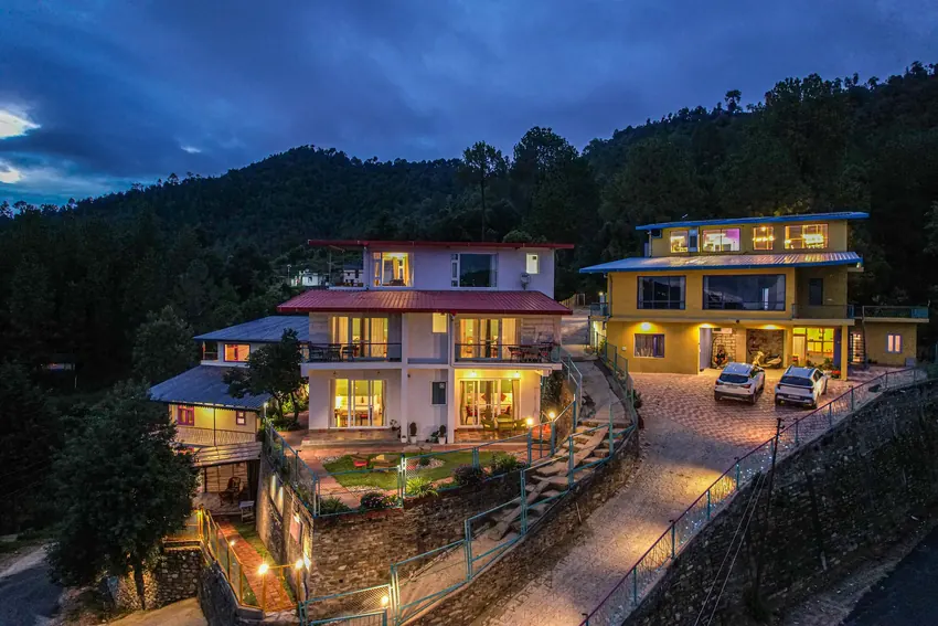 Multi-tiered resort buildings set on steep green mountain at Adrushya Estates