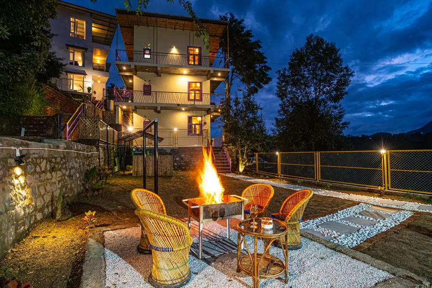 Outdoor seating area with chairs around bonfire setup and resort in background