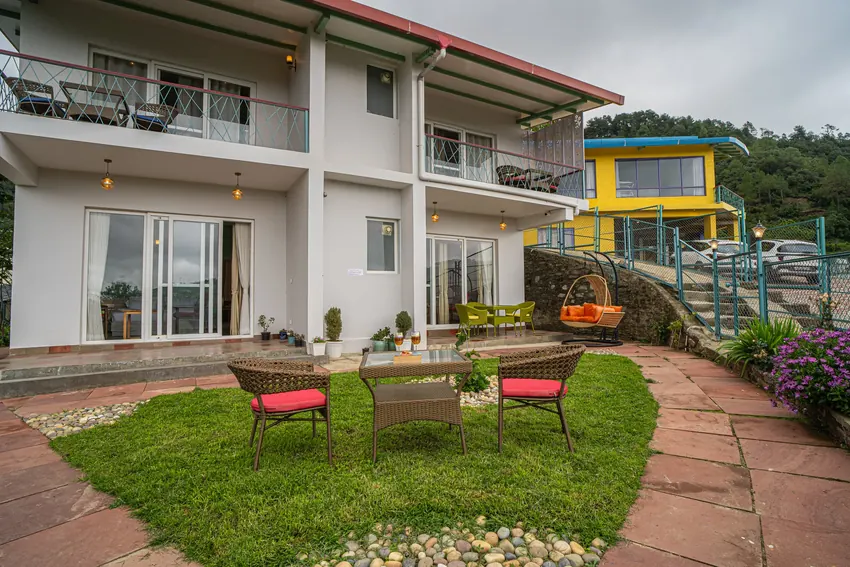 Balcony with lawn, chairs, and stone pathway leading to suite entrance at Adrushya Estates