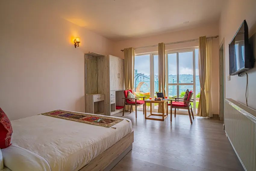 Bedroom with king size bed and balcony glass doors at Adrushya Estates